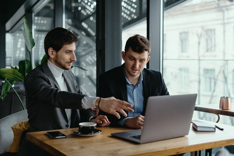 two-businessmen-pointing-at-laptop-screen-while-discussing