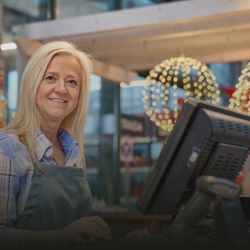 A smiling woman behind the cash counter