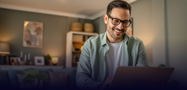 A man smiling at his laptop.