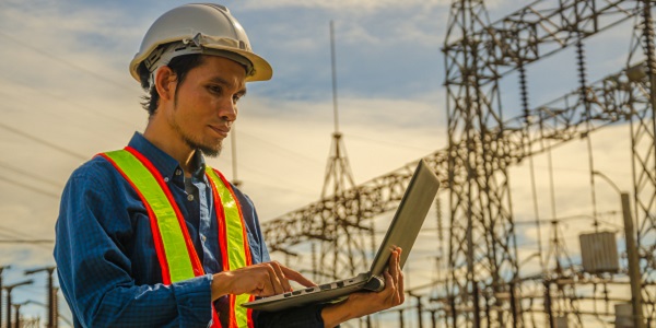 man using a laptop near a power grid